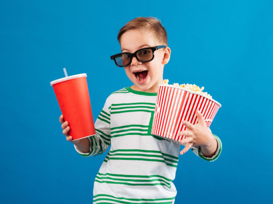 Kind mit Kino-Tüten-Popcorn und Getränk
